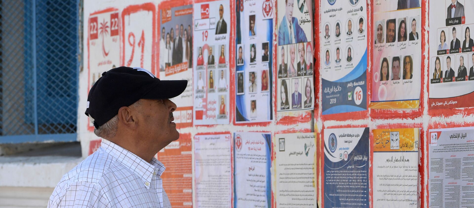 Un Tunisien devant les affiches des différents candidats aux législatives tunisiennes - Sputnik Afrique, 1920, 18.10.2019