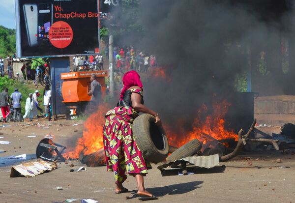 Femme brûlant des pneus pendant des funérailles qui ont suivi des manifestations, Guinée. - Sputnik Afrique
