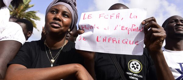 Un homme brandit une pancarte contre le franc CFA - Sputnik Afrique