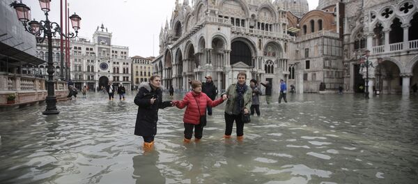 Des gens marchent dans l'eau sur la place Saint-Marc inondée à Venise, en Italie, le mercredi 13 novembre 2019 - Sputnik Afrique