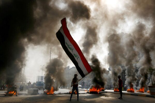 Manifestant agitant un drapeau irakien dans une rue de Nadjaf, Irak.  - Sputnik Afrique
