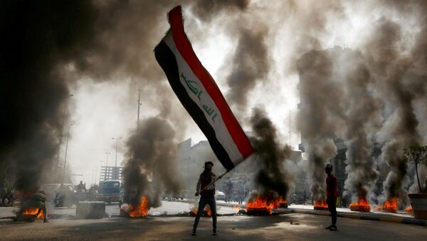  Протестующий с иракским флагом в руках во время акций протеста в Ан-Наджафе, Ирак - Sputnik Afrique