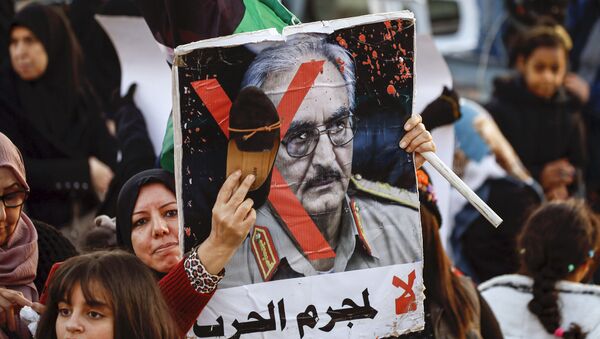 Une femme frappe avec sa chaussure le portrait de Khalifa Haftar lors d’une manifestation contre lui à Tripoli le 27 décembre 2019. - Sputnik Afrique