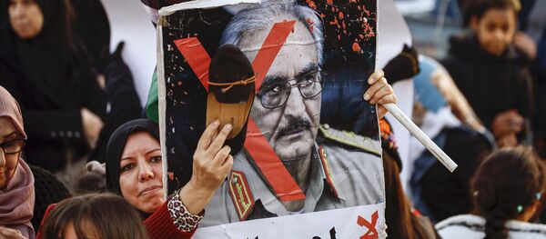 Une femme frappe avec sa chaussure le portrait de Khalifa Haftar lors d’une manifestation contre lui à Tripoli le 27 décembre 2019. - Sputnik Afrique