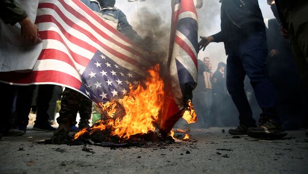 Des manifestants brûlent les drapeaux américain et britannique lors d'une manifestation contre l'assassinat du général iranien Qassem Soleimani - Sputnik Afrique