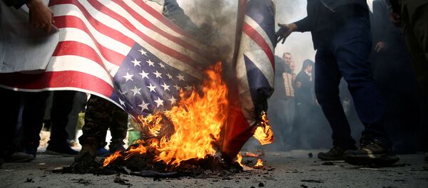 Des manifestants brûlent les drapeaux américain et britannique lors d'une manifestation contre l'assassinat du général iranien Qassem Soleimani - Sputnik Afrique