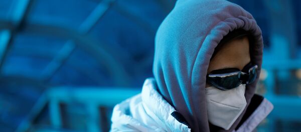 A woman wearing a face mask and goggles uses an escalator near Beijing Railway Station - Sputnik Afrique