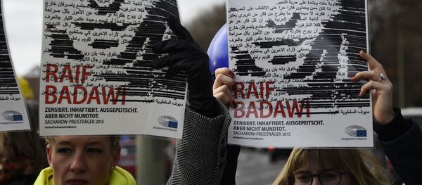 Des membres de l’ONG Amnesty International brandissent des portraits de Raif Badawi devant l’ambassade d’Arabie saoudite à Berlin, le 8 janvier 2016. - Sputnik Afrique
