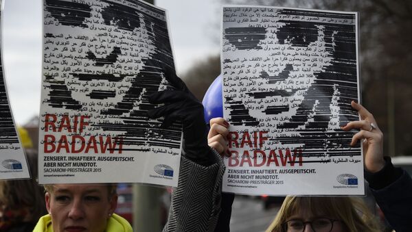 Des membres de l’ONG Amnesty International brandissent des portraits de Raif Badawi devant l’ambassade d’Arabie saoudite à Berlin, le 8 janvier 2016. - Sputnik Afrique