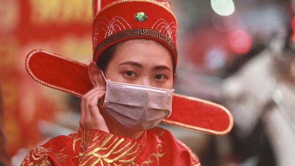 Une femme en costume traditionnel porte un masque dans un magasin à Hanoi, Vietnam, le lundi 3 février 2020 - Sputnik Afrique