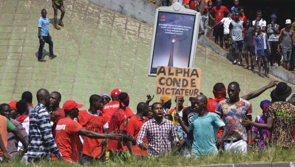 Un homme brandit une pancarte dénonçant la dictature d’Alpha Condé. - Sputnik Afrique