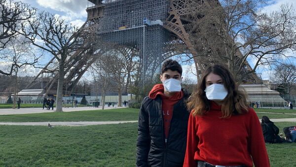 Des gens portant des masques se réposent au pied de la Tour Eiffel - Sputnik Afrique