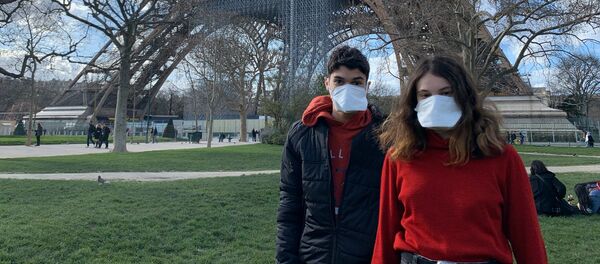 Des gens portant des masques se réposent au pied de la Tour Eiffel - Sputnik Afrique