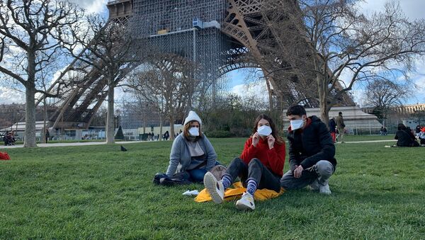 Des gens portant des masques se réposent au pied de la Tour Eiffel - Sputnik Afrique