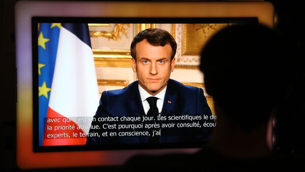 French President Emmanuel Macron is seen on a television screen as he speaks during a televised address to the nation on the outbreak of COVID-19, caused by the novel coronavirus, on March 16, 2020, in Paris - Sputnik Afrique