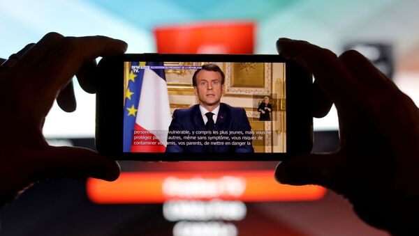 French President Emmanuel Macron is seen addresses the nation about the coronavirus disease (COVID-19) outbreak, on a mobile screen in this illustration picture - Sputnik Afrique