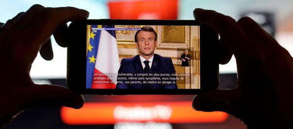 French President Emmanuel Macron is seen addresses the nation about the coronavirus disease (COVID-19) outbreak, on a mobile screen in this illustration picture - Sputnik Afrique