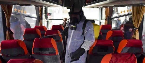 Un agent municipal désinfecte un bus contre le coronavirus à la station Kherrouba à Alger - Sputnik Afrique