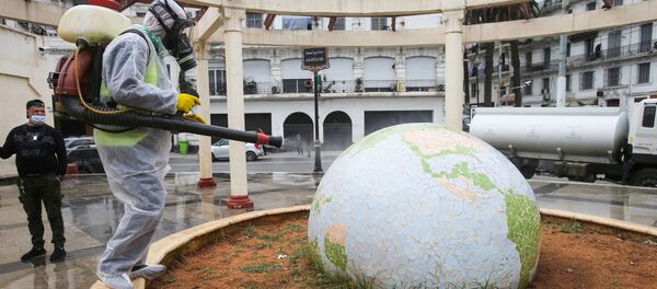 Un travailleur vêtu d'une combinaison de protection désinfecte une sculpture en forme de globe, à la suite de l'épidémie de coronavirus (COVID-19), à Alger, en Algérie, le 23 mars 2020. - Sputnik Afrique