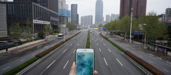 Показывающие полдень часы в мобильном телефоне на фоне пустой автомобильной дороги в Ухане в период пандемии коронавируса - Sputnik Afrique