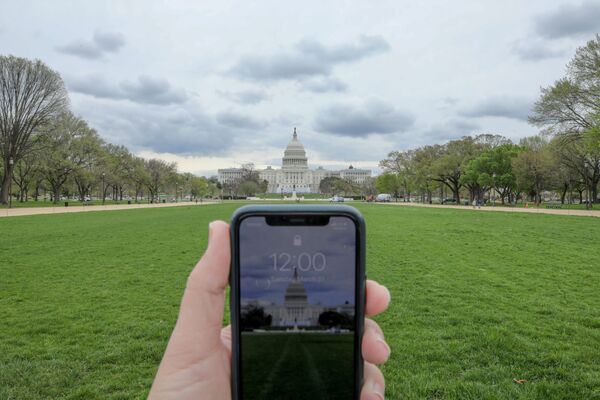 L'horloge d'un portable affichant midi en face du Capitole de Washington pendant la pandémie de coronavirus - Sputnik Afrique