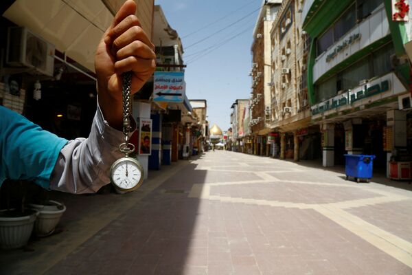 Une montre affichant midi dans la main d'un homme près d'un marché à proximité du mausolée de l'imam Ali à Najaf, en Irak, pendant la pandémie de coronavirus - Sputnik Afrique