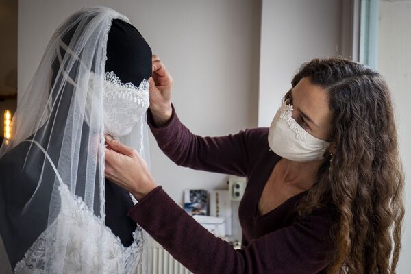 Un designer travaille sur une robe de mariage avec un masque de protection dans un magasin à Berlin - Sputnik Afrique