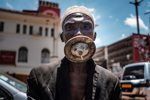Un homme portant un masque artisanal à Kampala, en Ouganda - Sputnik Afrique