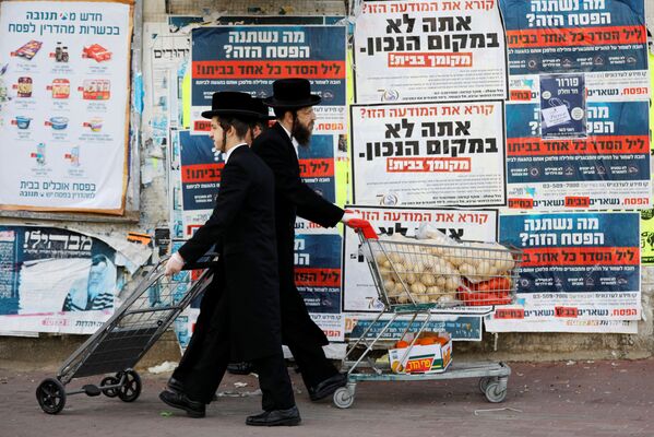 Des juifs ultraorthodoxes passent devant des panneaux d'information appelant à rester à la maison à cause du coronavirus à Ashdod, en Israël - Sputnik Afrique