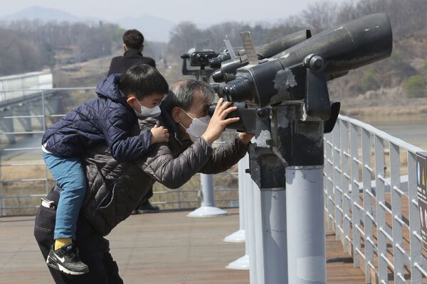 Un grand-père et son petit-fils regardent à la jumelle en direction de la frontière avec la Corée du Nord, Paju, Corée du Sud. - Sputnik Afrique