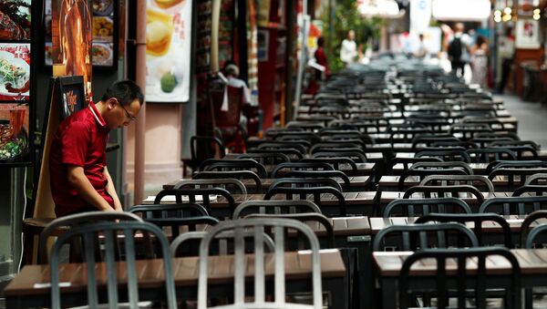 A restaurant promoter waits for customers at the largely empty Chinatown as tourism takes a decline due to the coronavirus outbreak in Singapore February 21, 2020 - Sputnik Afrique