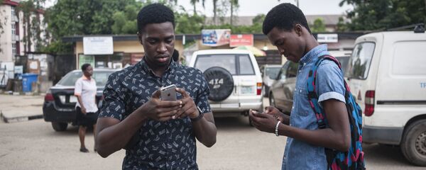 Deux jeunes scrutent leur téléphone portable. Deux jeunes scrutent leur téléphone portable. - Sputnik Afrique