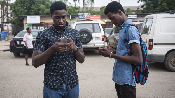 Deux jeunes scrutent leur téléphone portable. - Sputnik Afrique