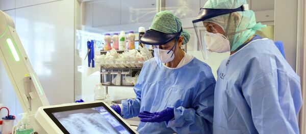 Сотрудники клиники в Бергамо в защитных масках рассматривают рентгеновский снимок легких больного коронавирусом пациента - Sputnik Afrique