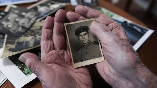 Le vétéran de la Grande guerre patriotique Alexeï Khavtourine regarde ses photos souvenirs  - Sputnik Afrique