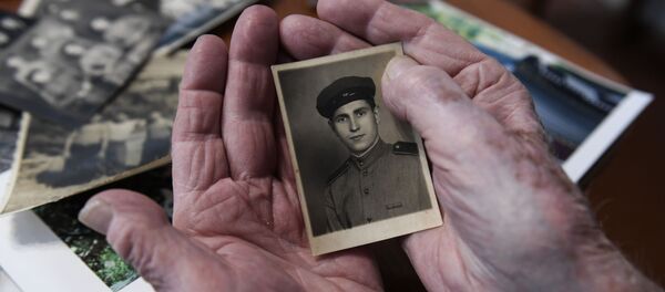Le vétéran de la Grande guerre patriotique Alexeï Khavtourine regarde ses photos souvenirs  - Sputnik Afrique
