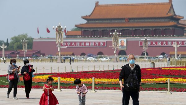 People wearing face masks following the coronavirus disease (COVID-19) outbreak walk past flower installations set up to mark the upcoming Labour Day holiday, at Tiananmen Square in Beijing, China April 29, 2020 - Sputnik Afrique