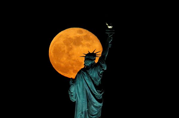 La pleine lune restera brillante dans le ciel pendant plusieurs jours. Sur la photo: la lune des fleurs sur fond de la Statue de la Liberté aux Etats-Unis. - Sputnik Afrique