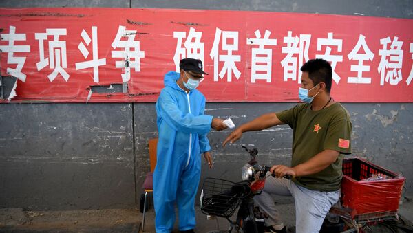 Le personnel de sécurité portant une combinaison de protection vérifie la température d'un homme sur une moto entrant sur le marché Xinfadi à Pékin, le 14 juin 2020 - Sputnik Afrique