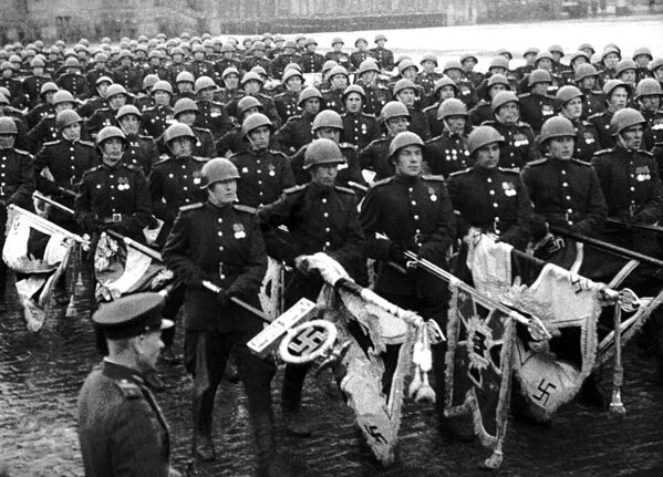 Durant le défilé, des étendards pris à l’ennemi et amenés de Berlin à Moscou par vol spécial, furent jetés au pied des murs du Kremlin. 
Sur la photo: une des scènes du film «La grande victoire du peuple soviétique», 24 juin 1945. - Sputnik Afrique