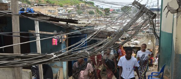 Des passants sous des fils électriques tombés d'un toit. - Sputnik Afrique
